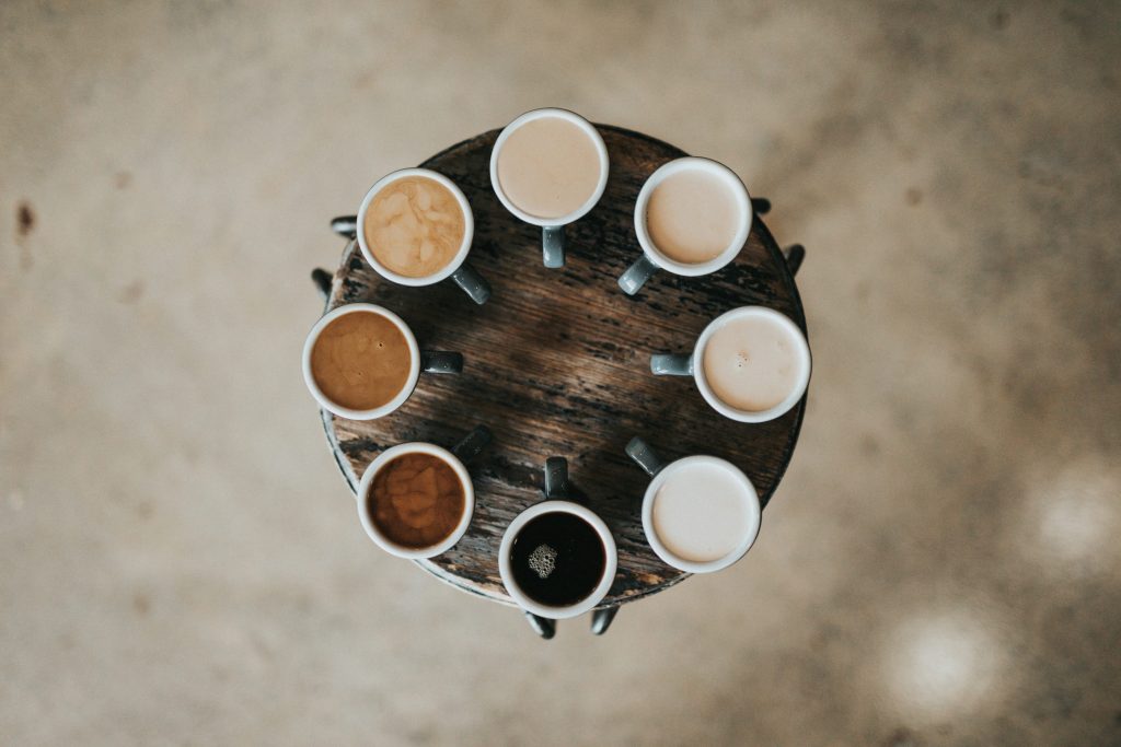 flat lay photography of eight coffee latte in mugs on round table